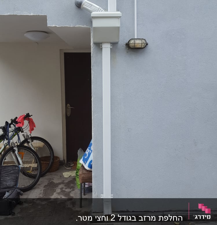 מרזב לבן מחובר לקיר אפור